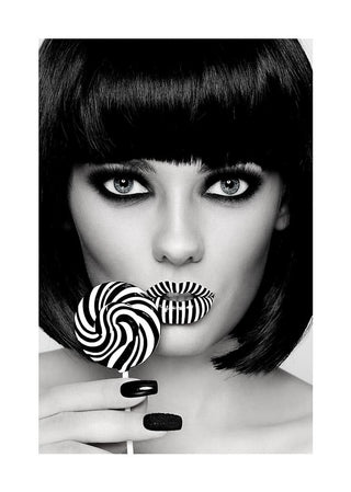Stylish woman with bold makeup holding a matching black and white striped lollipop near her lips.