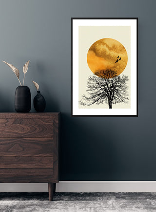 Poster of birds flying over a tree at sunrise, with an orange sun, displayed on a dark wall above a wooden dresser.