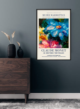 Framed Claude Monet flower painting poster on a dark wall above a modern wood dresser with vase decor.