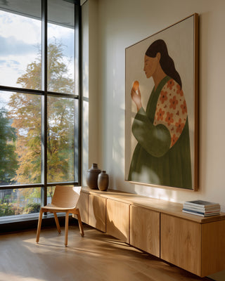 Large artwork of a woman holding an apple, displayed in a modern room with natural light and wooden furniture.