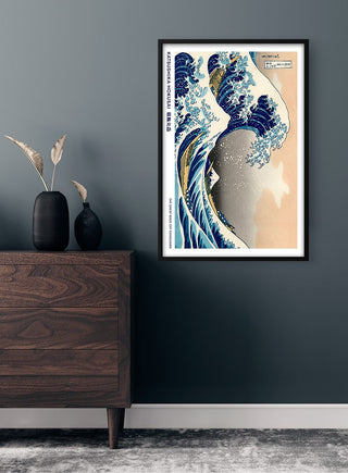 Framed print of Hokusai's The Great Wave displayed on a dark wall above a wooden dresser with vase.