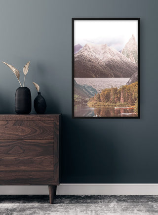 Framed Mountain lake and trees Plakat displayed on a dark wall above a wooden dresser with decorative vase.