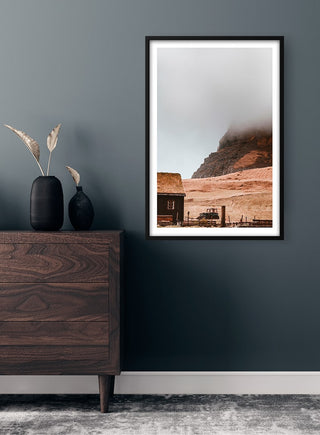 Framed Cloudy Mountain Plakat print displayed above a wooden dresser in a modern, minimalist room.