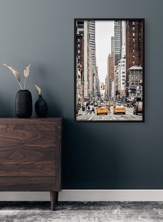 Framed New York City plakat featuring yellow taxis and tall buildings, displayed above a dresser in a modern room.