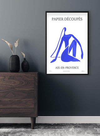 Blue By Casette Bleue poster with abstract blue figure, framed and hanging above a dark wood dresser in a modern living room.