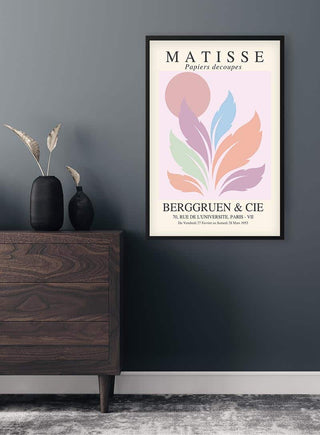 Framed Matisse Inspired Pink Sun No. 02 poster with abstract pastel shapes, displayed above a wooden dresser.