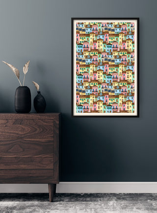 Framed Colorful Houses Plakat hanging on a dark wall above a wooden dresser in a modern room.