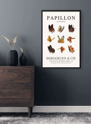 Brown Papillon poster with various butterfly illustrations, framed and displayed above a modern wooden dresser.