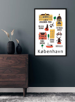 Colorful København city landmarks poster on a dark wall above a wooden cabinet with decorative vases.