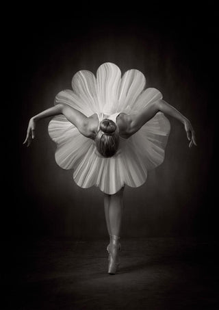 Ballet dancer in a flower-shaped tutu, arms gracefully extended, photographed in elegant black and white.