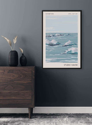 Framed Studio Havde Seascape print hanging on a dark gray wall above a wooden dresser with vase decor.