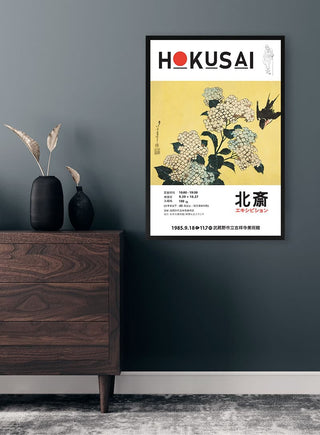 Framed print of Katsushika Hokusai’s "Hydrangea and Swallow" hanging on a modern dark wall above a wooden dresser.