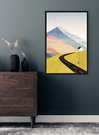 Framed "Cycling Home - Henry Rivers" print on a wall, showing a cyclist, road, mountains, and house.