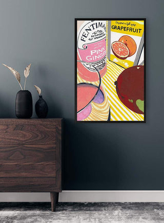 Framed poster featuring Fentimans Pink Ginger and grapefruit on a modern, dark-toned wall above a wooden dresser.