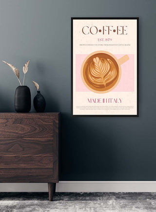 Framed coffee art print featuring a latte with leaf-shaped foam, displayed above a wooden dresser.