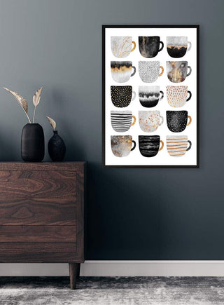 Framed art print of 12 stylish coffee cups in black, white, and gold tones displayed above a modern dresser.