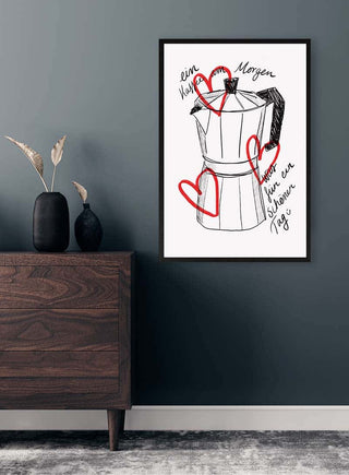 Framed art print of a moka pot with red hearts and handwritten text "Ein Kaffee am Morgen" on wall above dresser.