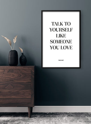 Framed "Talk to yourself like someone you love" quote poster on a wall above a wooden dresser.