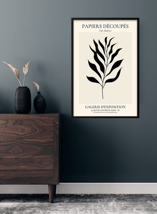French Art inspired black leaf poster in a frame, hanging above a dresser with decorative vases.