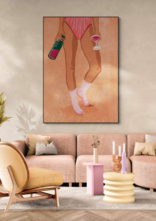 Art print of a woman in socks holding wine, displayed above a stylish modern sofa set.