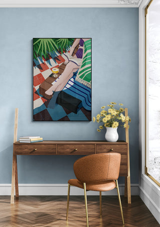 Just one more chapter - Goed Blauw art print hanging above a wooden desk with a vase of yellow flowers.