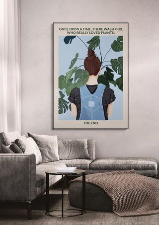 Wallchart showing a girl with a bun facing large green plants, hung above a sofa in a modern living room.
