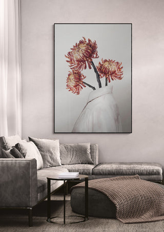 A framed "In Bloom" artwork by Gabriella Roberg hangs above a modern gray sofa in a cozy living room.