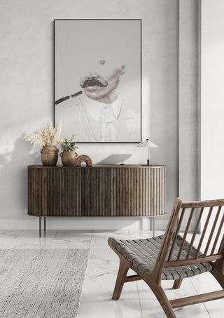 Framed "Man" by Gabriella Roberg hanging above a wooden sideboard in a modern, minimalist living room.