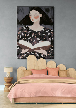 Framed "The Reader" by David Wolf hanging above a modern bed with pink bedding and a wooden headboard.