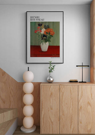 Bouquet De Fleurs by Henri Rousseau art print hanging above a modern wooden cabinet in a stylish room.