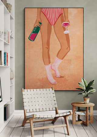 Art print of a woman's legs in pink socks holding wine and glass, displayed stylishly on a modern wall.
