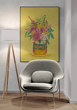 Framed print of colorful flowers in a vintage honey can, displayed above a modern chair and lamp.