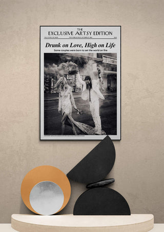 Framed "Drunk On Love Artsy Edition" poster displayed above modern abstract sculpture on a shelf.