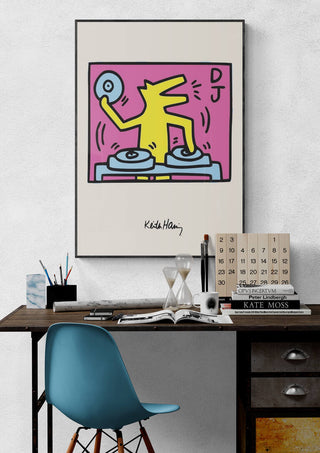 Framed print of Keith Haring's "DJ" featuring a yellow figure spinning records on a wall above a desk.