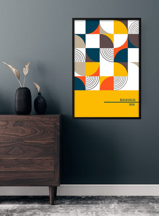 1919 Bauhaus Poster #4 with geometric shapes in bold colors, framed and hung above a wooden dresser.