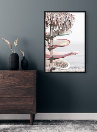 Framed poster of colorful surfboards stacked by the beach, displayed above a wooden dresser in a modern room.