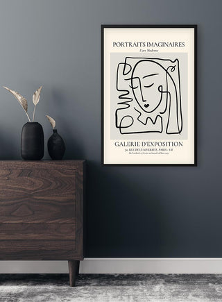 Framed Portraits Imaginaires Grey Plakat with abstract face illustration on a dark wall above a wooden dresser.