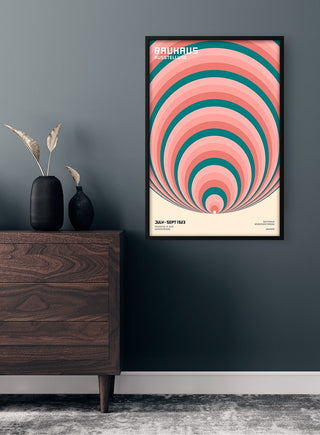 Framed Bauhaus Big Circles Plakat with concentric circles in blue, pink, and cream on a dark wall above a wooden dresser.