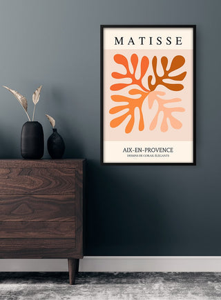 Framed Matisse Inspired Orange Flower Plakat with abstract floral shapes displayed on a wall above a wooden dresser.