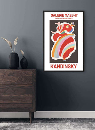 Framed Kandinsky Forme Rouge Plakat poster on dark wall above wooden dresser with vases and dried flowers.