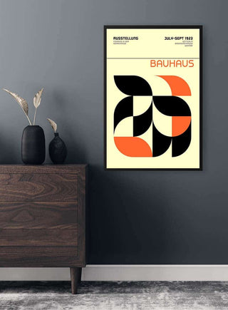 Framed Bauhaus Orange Weimar Ausstellung Plakat with geometric black and orange shapes on a wall above a dresser.