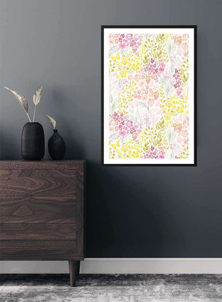 Poster with pink and yellow flowers hanging on a dark wall above a wooden dresser with vases.