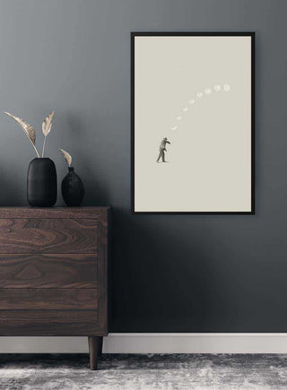 Framed "Lucky shot" by Maarten Léon on a gray wall above a modern wooden dresser with black vases.