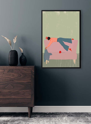 Framed RocAso - Jotadejai artwork of a person lounging on a pink couch, displayed above a wooden dresser.