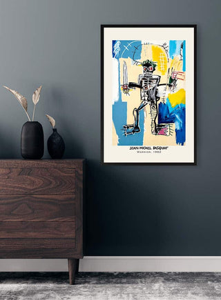 Framed "Warrior" by Jean Michel Basquiat displayed on a dark wall above a wooden dresser with vases.