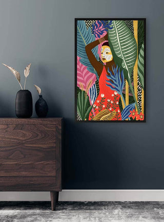 Framed "Mask" by Maja Tomljanovic on grey wall above wooden dresser in modern interior setting.