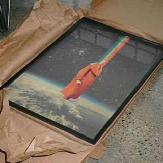 Framed Spacecolor - Frank Moth art print with a cosmic scene, partially unwrapped on a textured floor.