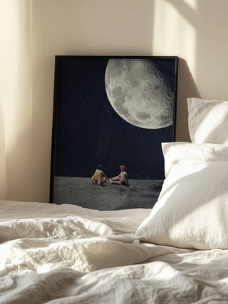 Framed "I Gave You the Moon for a Smile" by Frank Moth resting on a bed with white bedding.