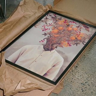 Framed Bright Bloom by Frank Moth print featuring a head replaced with vibrant flowers, lying on brown wrapping paper.