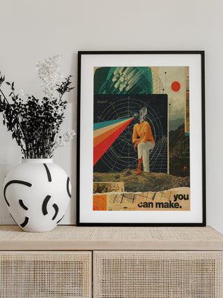 Framed "You Can Make It Right" by Frank Moth on a cabinet, next to a white vase with black patterns and dried flowers.